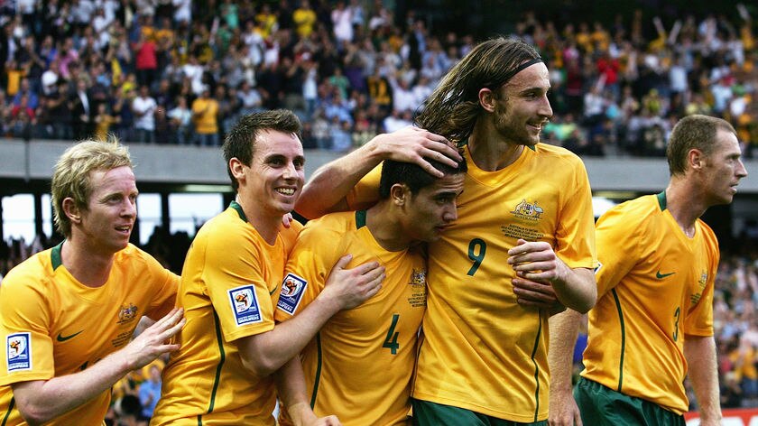Gelling beautifully... goal scorer Tim Cahill is given a pat on the back by his fellow Socceroos.