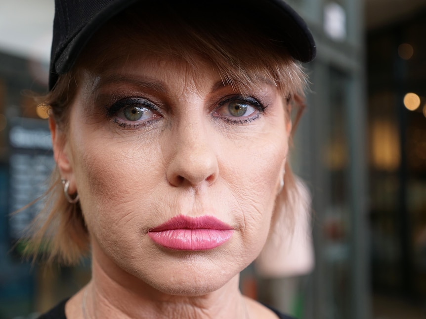 a woman stares into the camera with a serious expression on her face