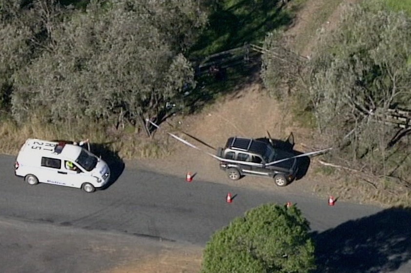 Two cars near a fence on a road.