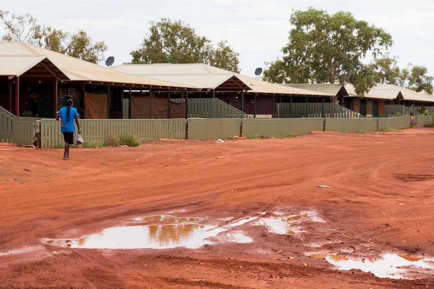 A mother carries a child down a street in the West Kimberley's Bidyadanga Aboriginal community.