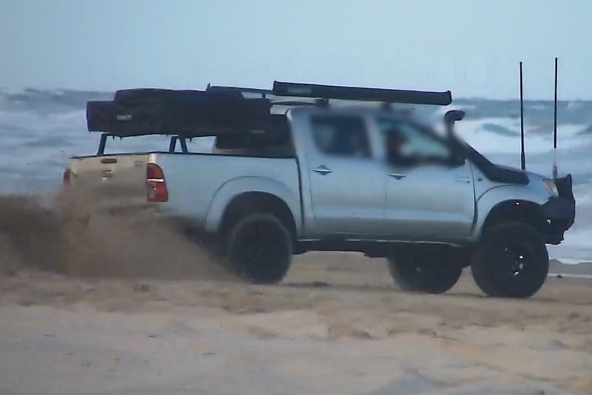A 4 wheel drive vehicle hooning on a beach.