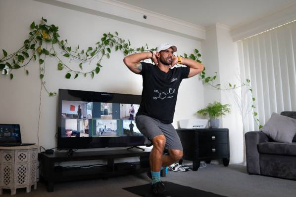 A man exercising in front of a video conference call