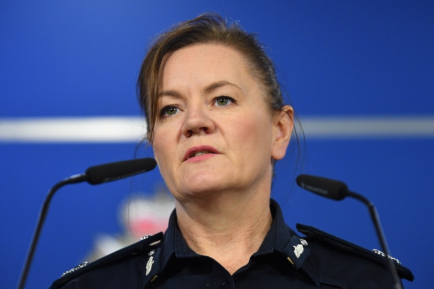 Assistant Commissioner Libby Murphy stands behind microphones at a lectern in the Victoria Police media briefing room.