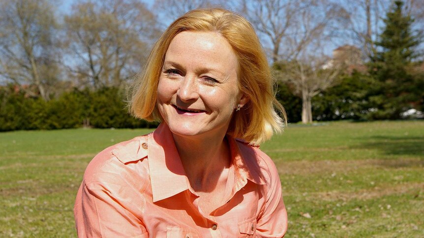 A smiling blonde middle-aged woman on grass