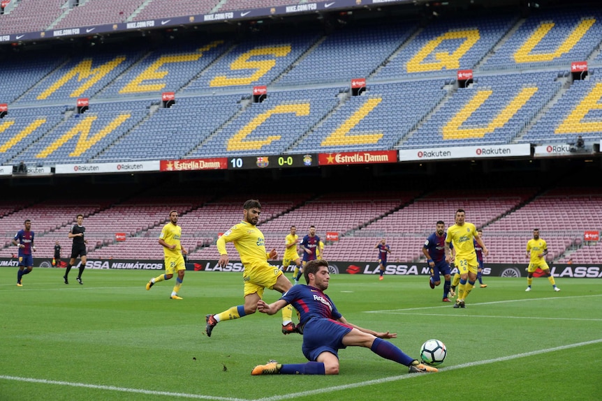Sergi Roberto plays the ball in front of empty Nou Camp stands