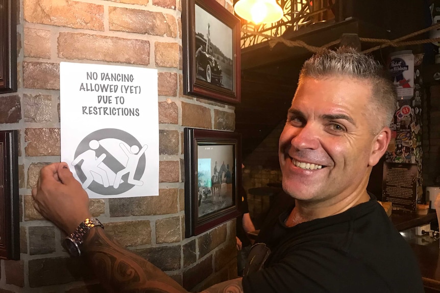 Man smiles next to no dancing sign.