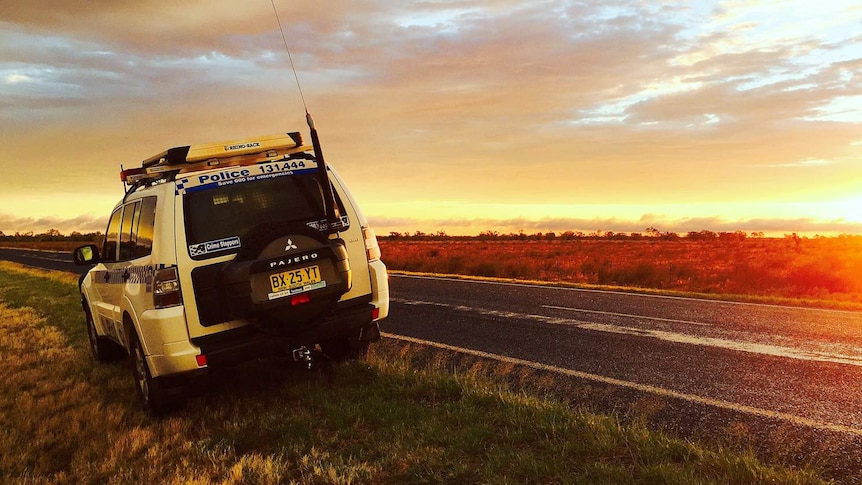 Police car on side of road at sunset