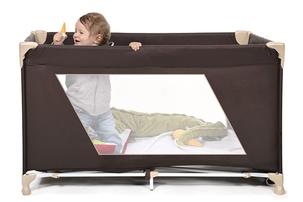 A young child plays in a foldable cot.