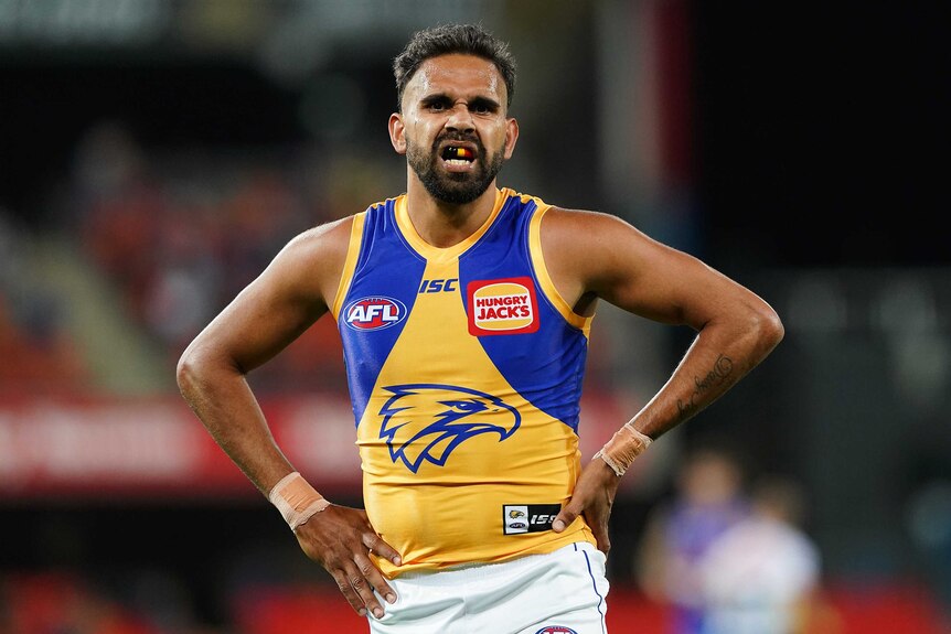 A West Coast Eagles AFL player stands with his hands on his hips during a match in the 2020 season.