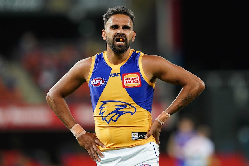 A West Coast Eagles AFL player stands with his hands on his hips during a match in the 2020 season.