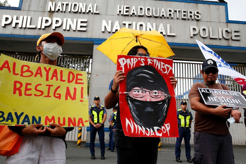 Protesters display placards during a brief rally at the Philippine National Police headquarters