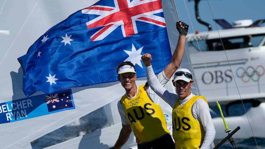 Two men sailing by their sailing boat celebrating after winning gold at the Olympics