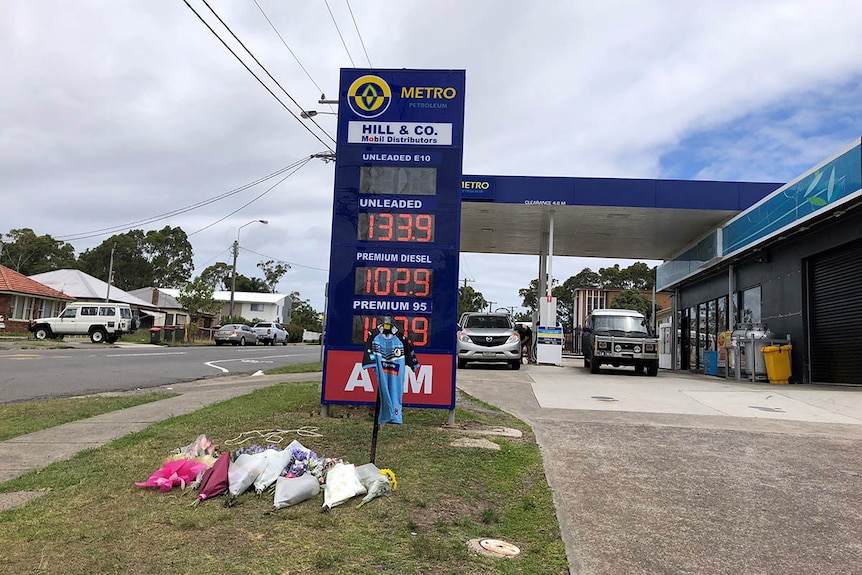 A service station with a football jersey and flowers laid out the front.