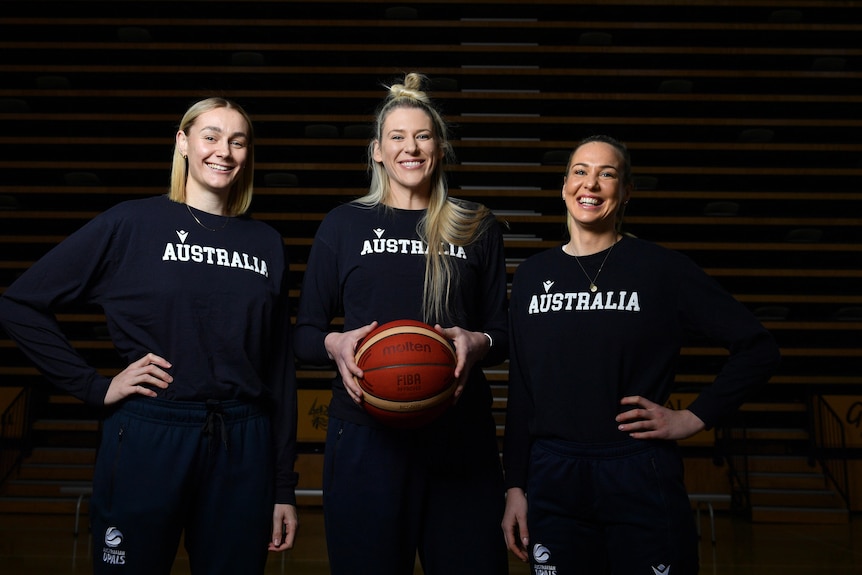 Three Australian women's basketballers pose for the camera and smile.