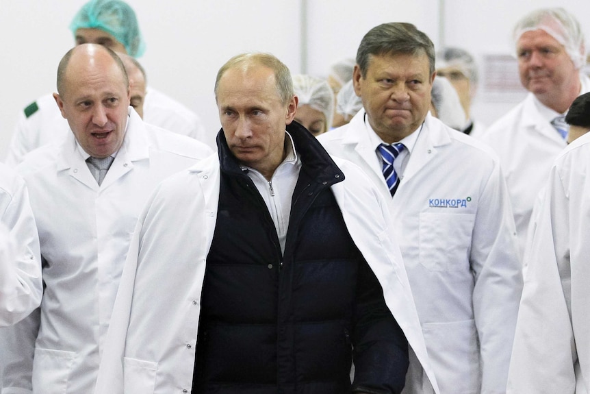 Businessman Yevgeny Prigozhin, left, stands next to Vladimir Putin and other men.