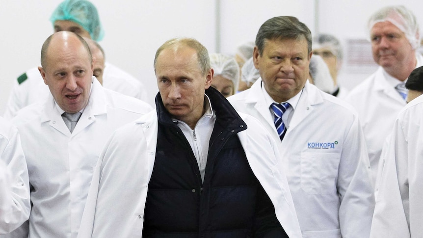 Businessman Yevgeny Prigozhin, left, stands next to Vladimir Putin and other men.