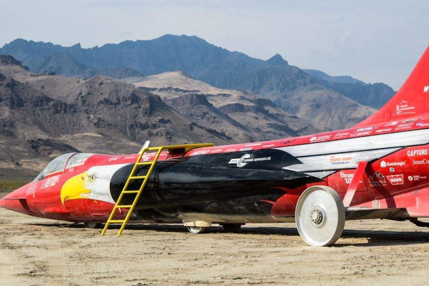 Jet-car speed racer, the North American Eagle, is parked against a rocky mountain range in the Alvord Desert.