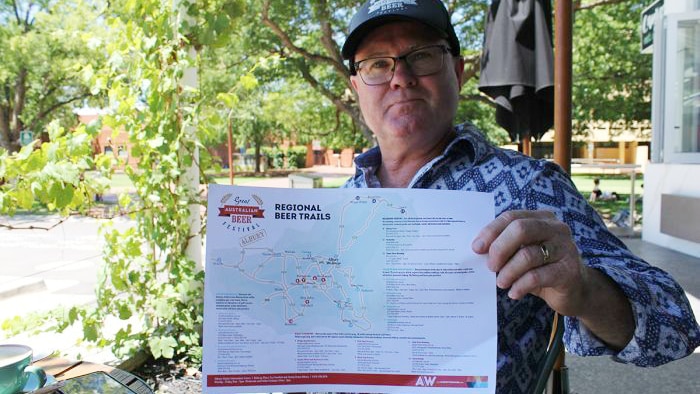 Great Australian Beer Festival Co-Director Michael Ward seated at a table holds the beer map.