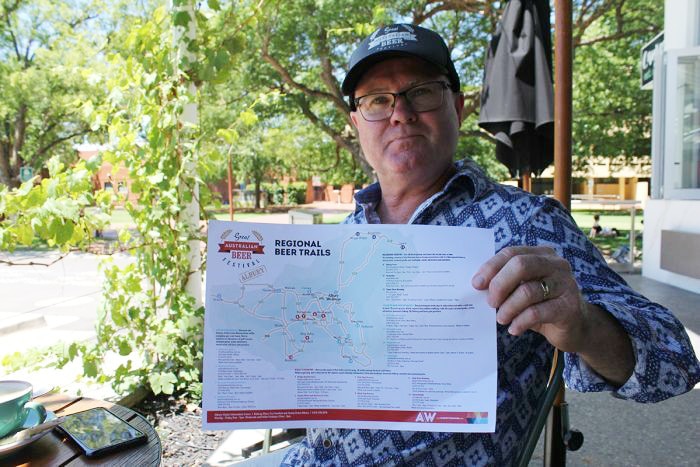 Great Australian Beer Festival Co-Director Michael Ward seated at a table holds the beer map.