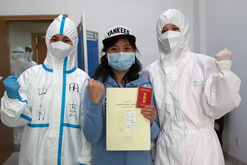 Two people in PPE protective gear, and a person holding up a passport.