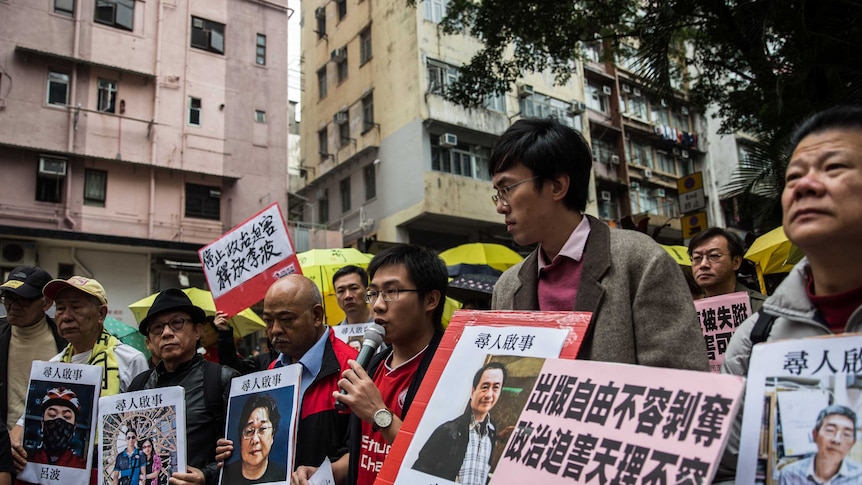 Protestors hold up missing person notices