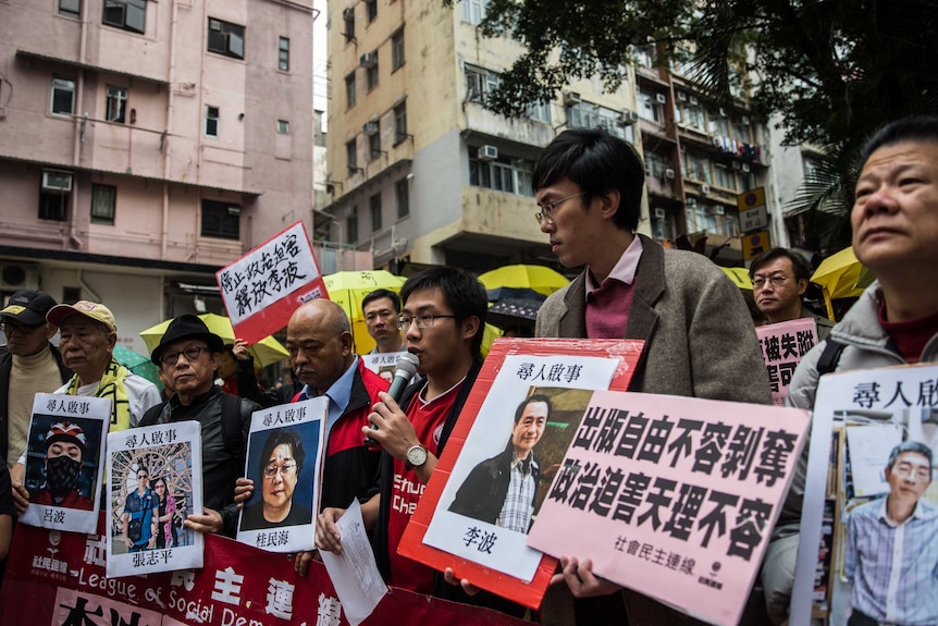 Protestors hold up missing person notices