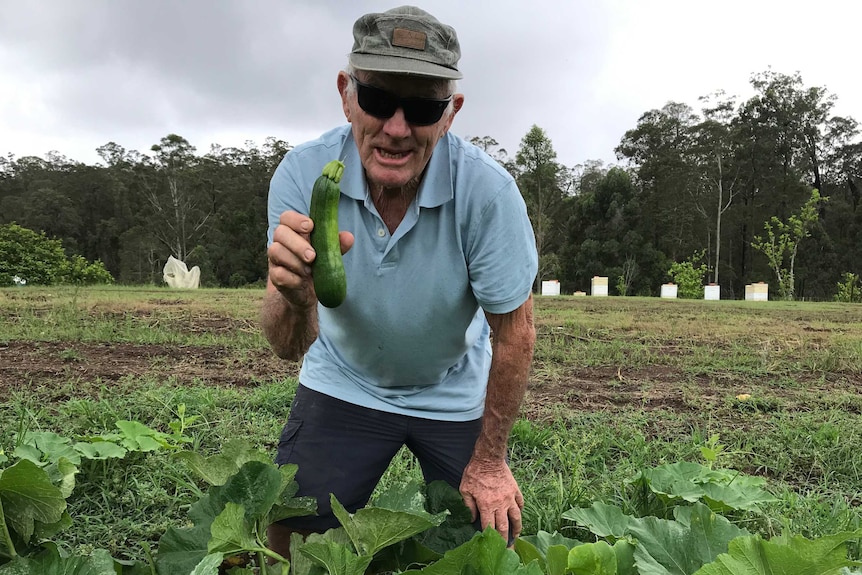 A man holding up a cucumber.