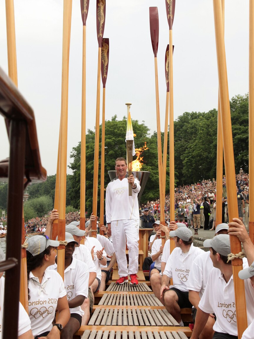 Olympic Gold Medallist Matthew Pinsent holds Olympic flame on the Royal rowbarge Gloriana