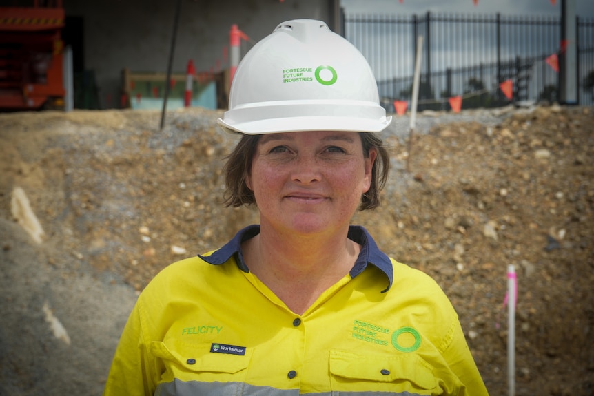 A woman smiles at the camera on a construction site