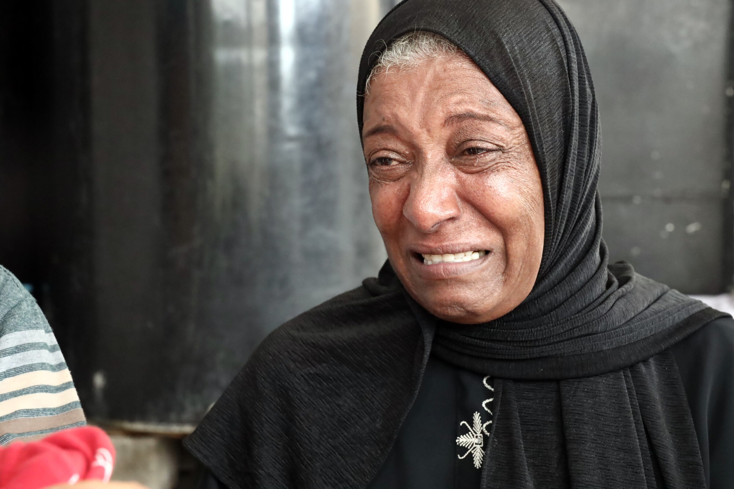 An older woman in a hijab crying.
