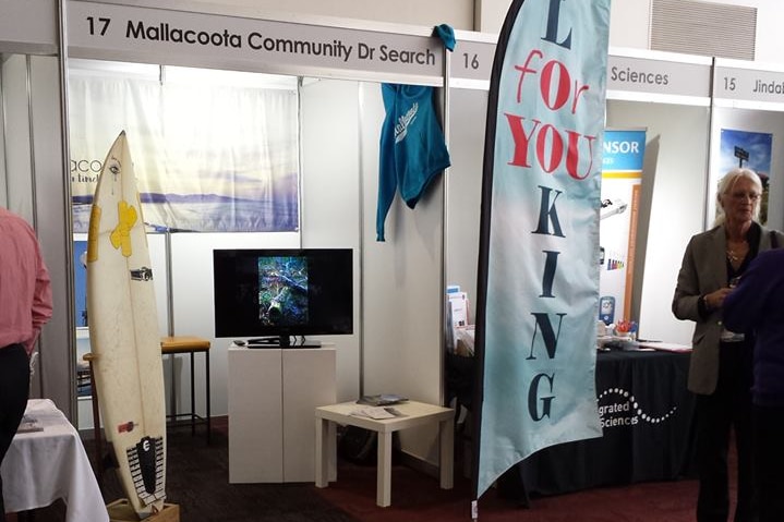 A stall that says Mallacoota Community Dr Search with a surfboard.