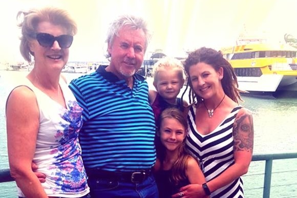 A woman, man, two young kids and a young woman pose for a family portrait.