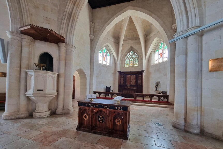 The interior of a sandstone church, with high sculptural windows of stained glass