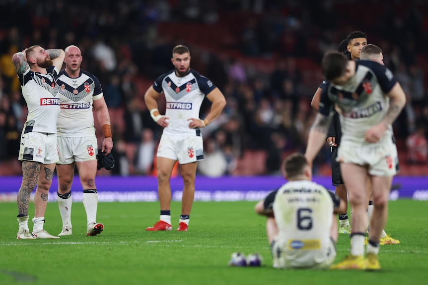 Seorang pemain liga rugby Inggris mengatupkan tangannya di belakang kepalanya dan melihat ke atas saat rekan satu timnya terlihat kelelahan dan sedih.