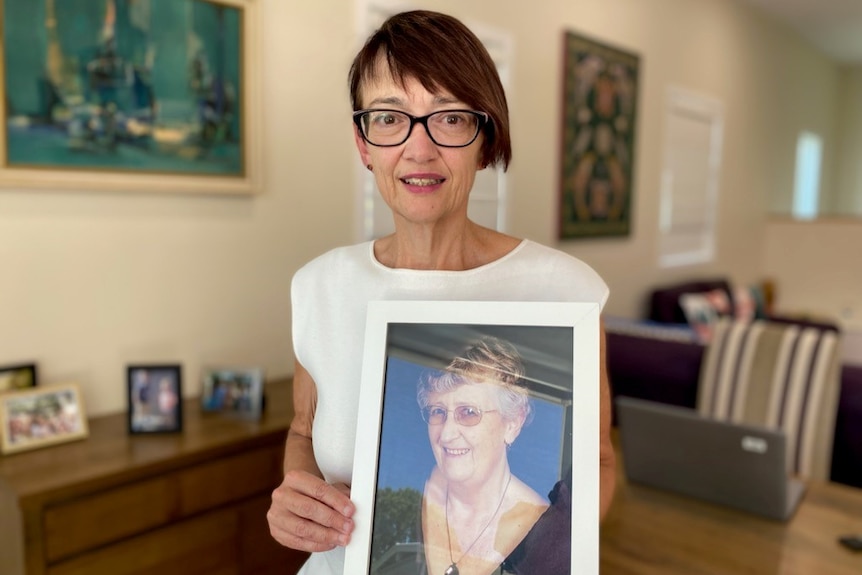 Anne in her home holding a framed picture of Vera