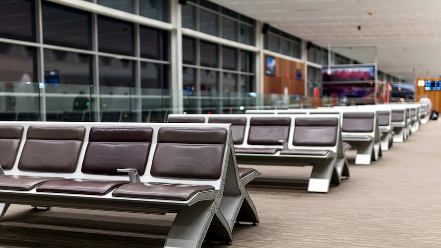 Rows of empty, brown and metal seats stretch out into the distance in a departure lounge at Adelaide International Airport.