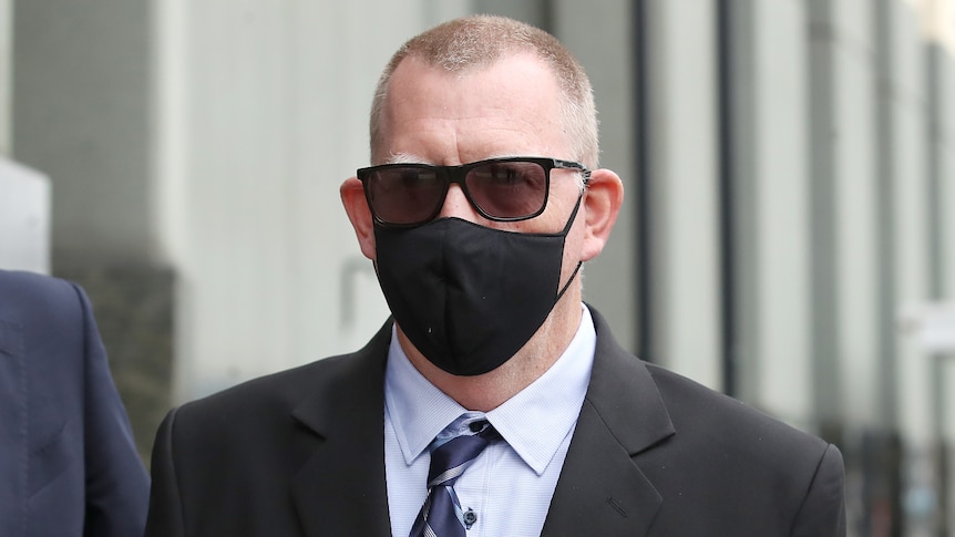 A man with dark black sunglasses and black mask.