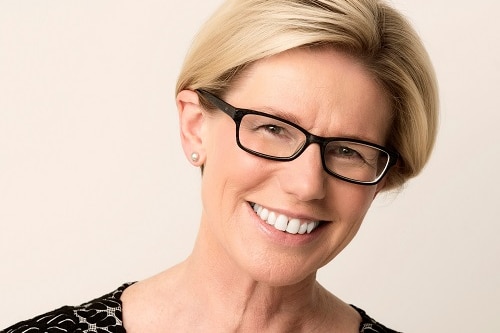 Woman with blonde hair and glasses smiling