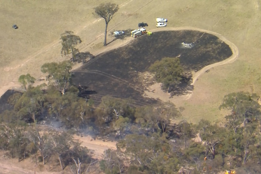An aerial shot of a plane crash scene surrounded by charred grass.