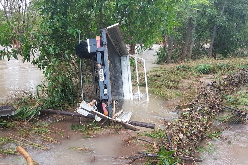 Custom trailer on its side in floodwater.