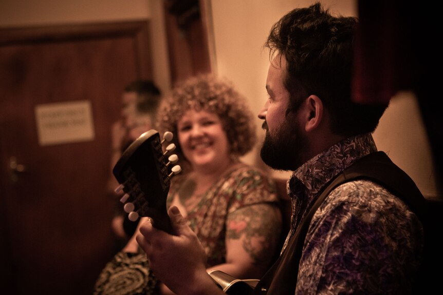 male and female musicians smiling in a narrow hallway, sidestage