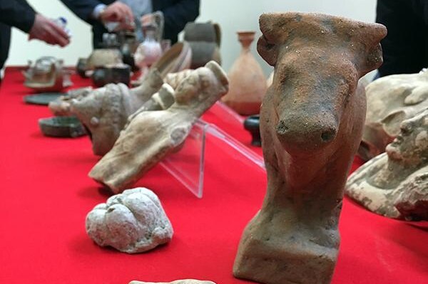 Multiple items are on a red table, including what looks like a cow or bull statue