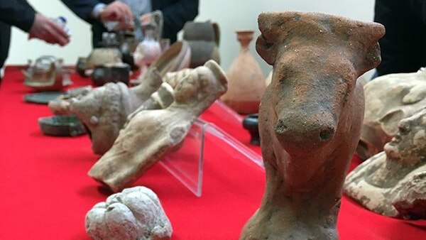 Multiple items are on a red table, including what looks like a cow or bull statue