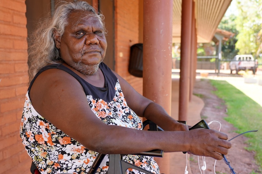 An elderly Aboriginal woman sits on her walker  