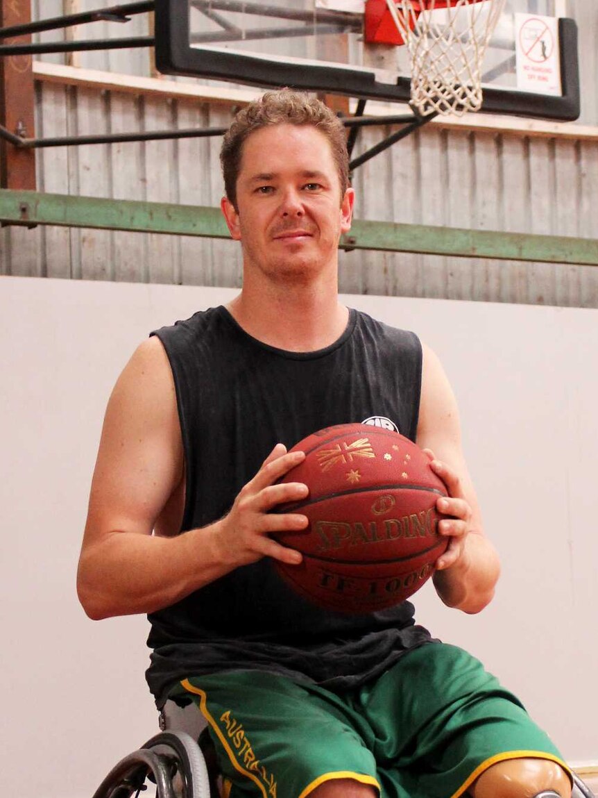 A man in a wheelchair on a basketball court, holding a basketball.
