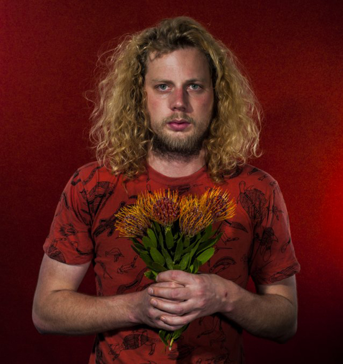 A portrait of James holding native flowers.