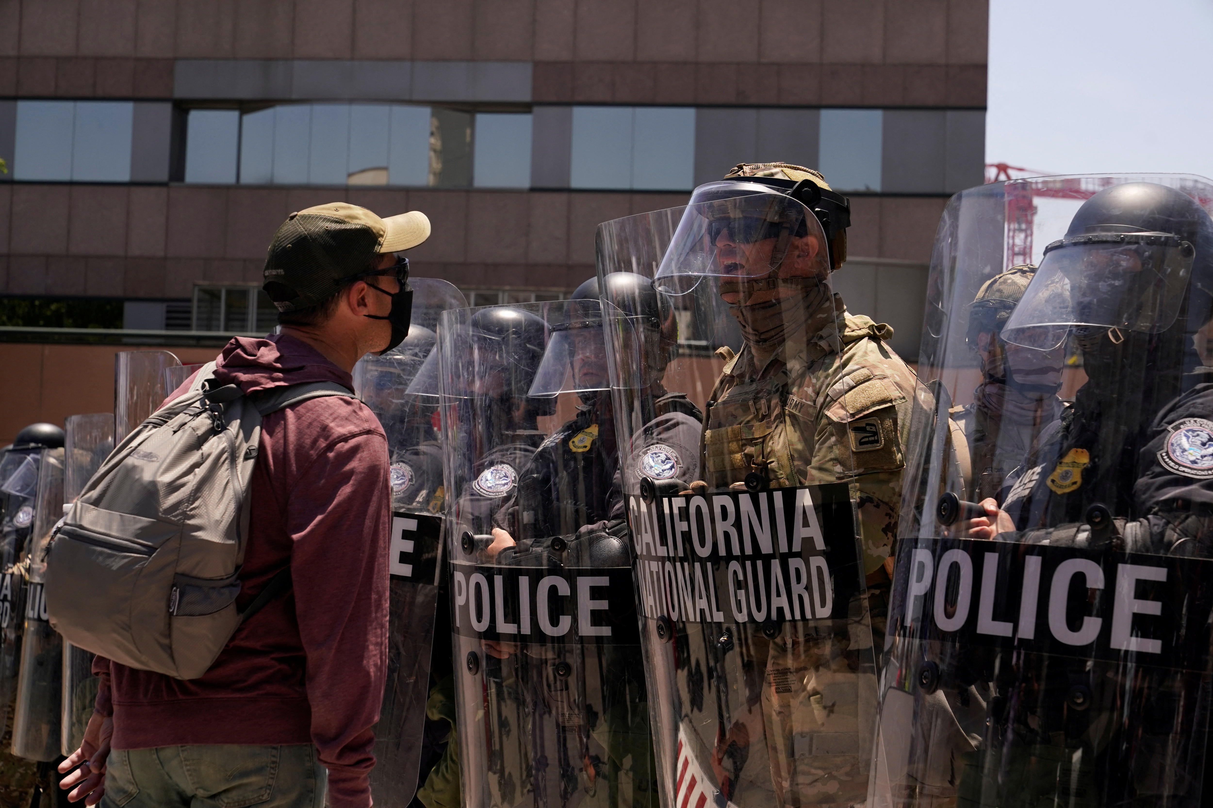 A man yells at a National Guard member in camo fatigues standing in a police barrier.