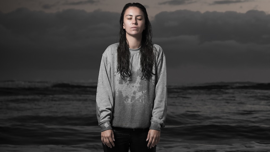 Image of Amy Shark standing in the ocean with her eyes closed