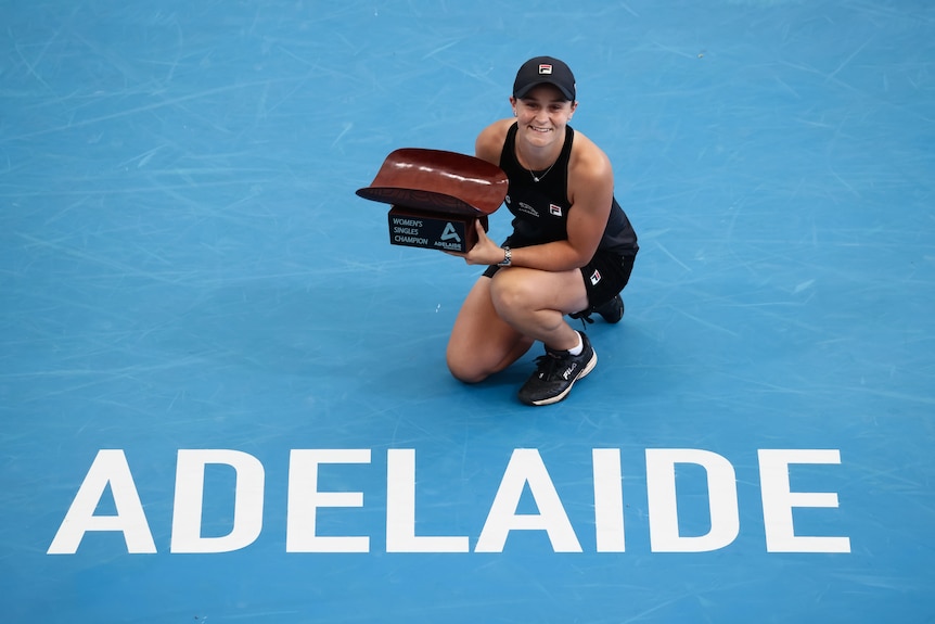 Tennis player poses with trophy