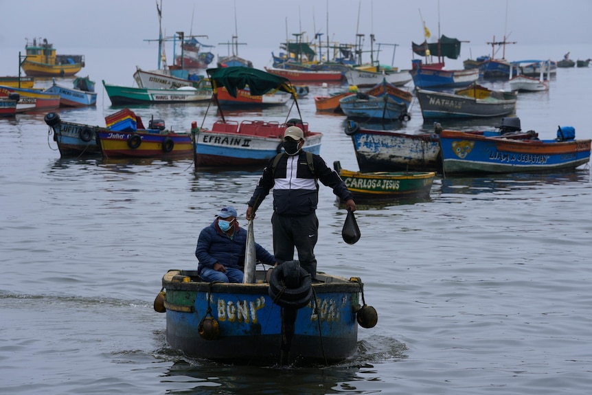 Un hombre está parado en un bote con basura.